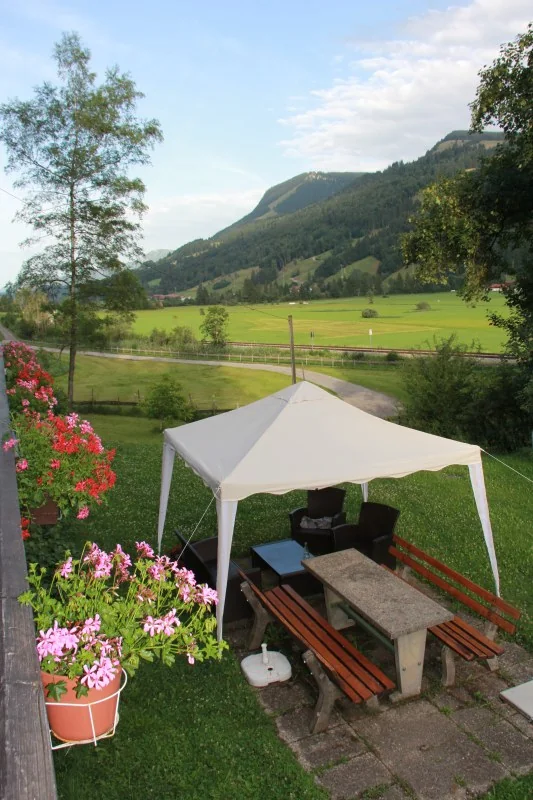 Blühender Garten mit einem schattigen Pavillon und einer Sitzgruppe