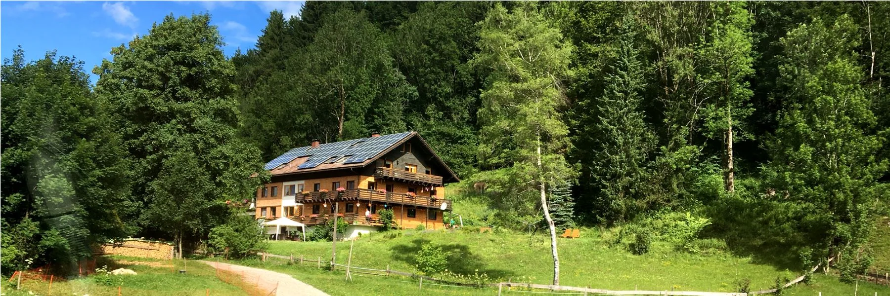 Haus Lichtblick liegt am sonnigen grünen Hang, eingerahmt von Allgäuer Wiesen und Wald