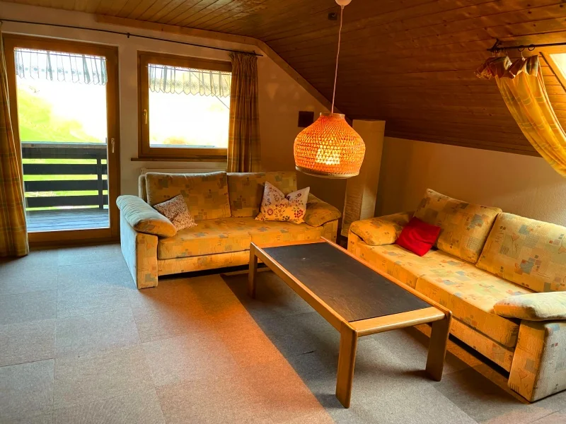 Das helle Wohnzimmer der Ferienwohnung Morgensonne mit Sofas, Holzmöbeln und Zugang zum Balkon